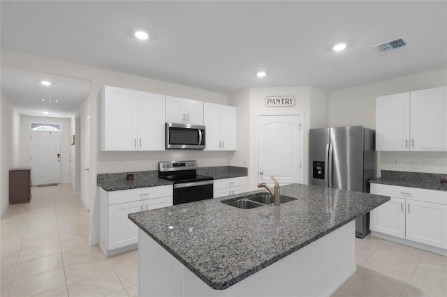 kitchen featuring appliances with stainless steel finishes, light tile patterned floors, sink, and a kitchen island with sink