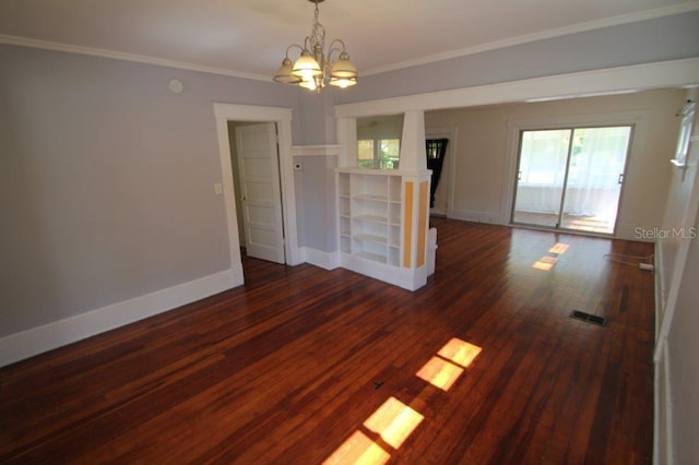 spare room featuring dark hardwood / wood-style flooring, ornamental molding, and an inviting chandelier