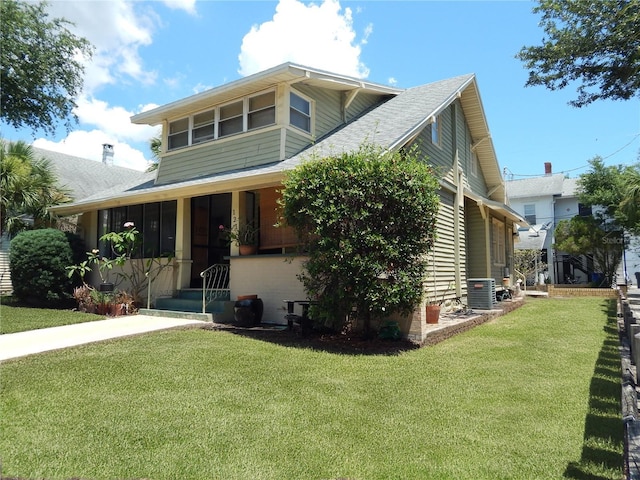 view of front facade with a sunroom, cooling unit, and a front yard