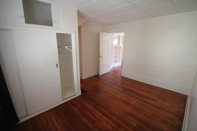 interior space featuring a paneled ceiling and dark hardwood / wood-style floors