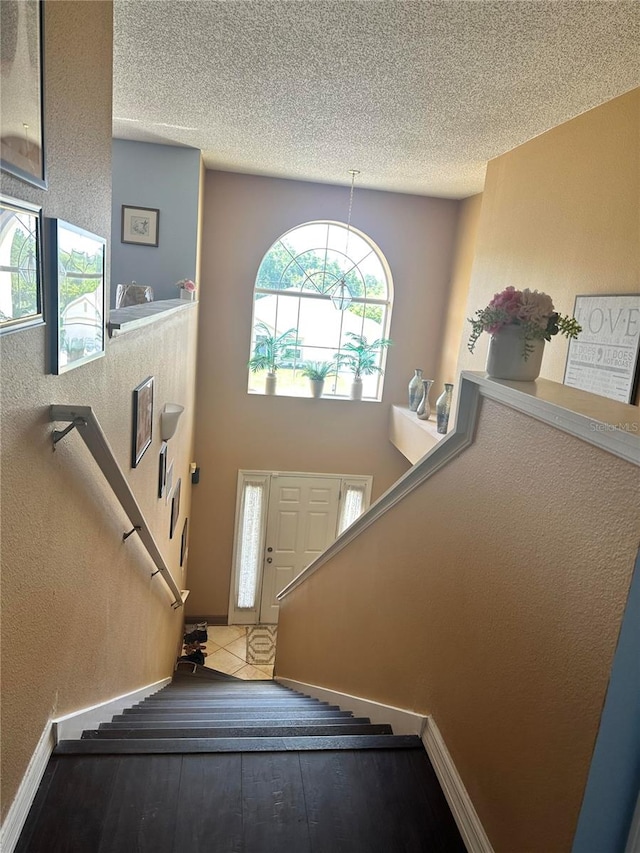 stairway featuring tile patterned floors, a textured ceiling, and a high ceiling