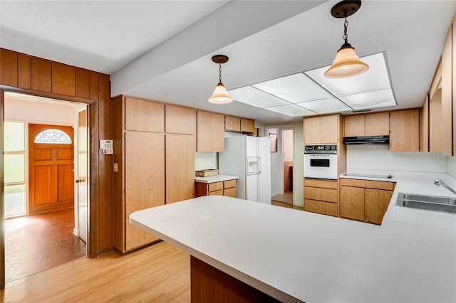 kitchen featuring kitchen peninsula, white appliances, hanging light fixtures, and sink