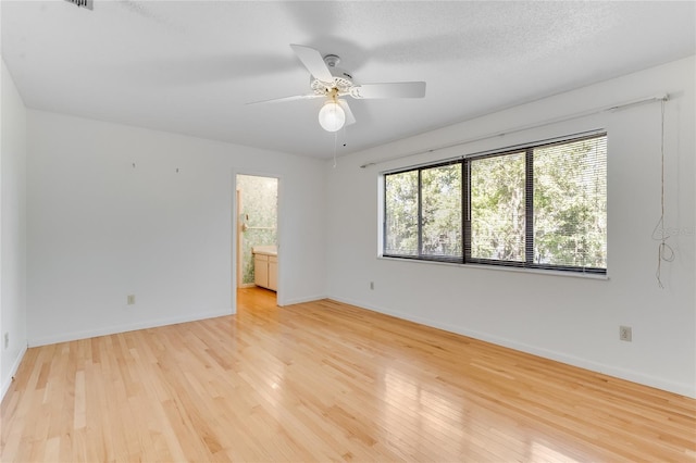 unfurnished room with a textured ceiling, light wood-type flooring, and ceiling fan