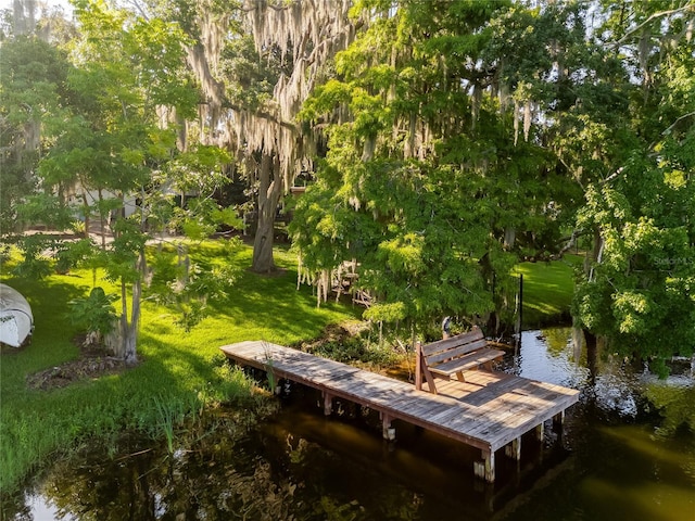 surrounding community with a dock, a yard, and a water view