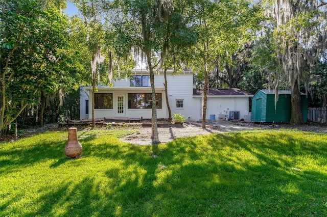 rear view of property featuring central AC, a yard, and a storage unit