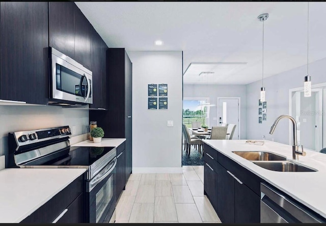 kitchen with sink, appliances with stainless steel finishes, decorative light fixtures, and light tile patterned floors