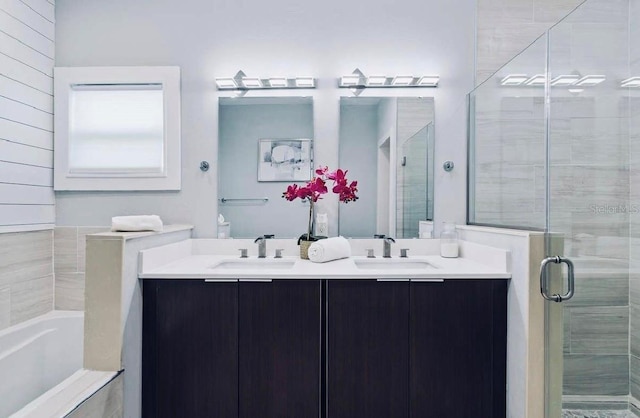 bathroom with dual vanity and separate shower and tub