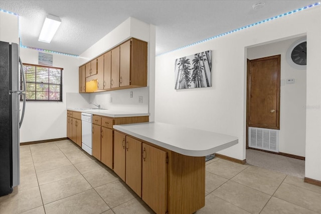 kitchen with stainless steel refrigerator, light tile patterned floors, a textured ceiling, kitchen peninsula, and dishwasher