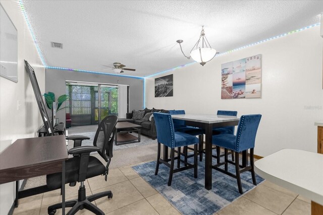 dining space featuring tile patterned flooring, ceiling fan, and a textured ceiling