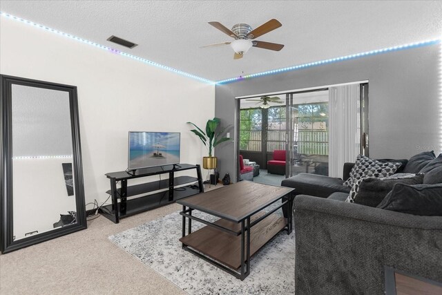 carpeted living room featuring a textured ceiling and ceiling fan