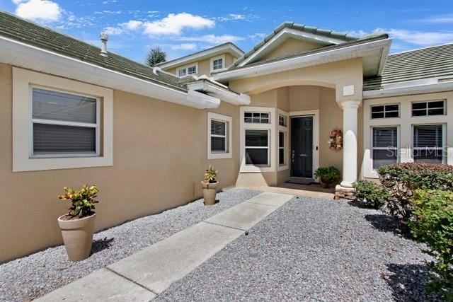 entrance to property with stucco siding and a tile roof