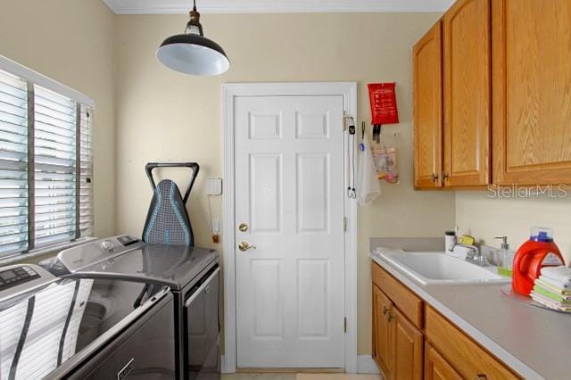 laundry room featuring washer and clothes dryer, cabinets, ornamental molding, and sink