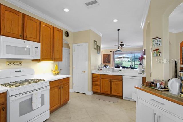 kitchen with ceiling fan, sink, white appliances, light tile patterned flooring, and ornamental molding