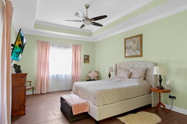 bedroom featuring dark hardwood / wood-style flooring, a raised ceiling, ceiling fan, and crown molding