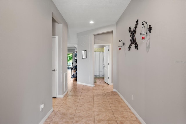 hall featuring light tile patterned floors and a textured ceiling