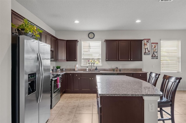 kitchen featuring sink, a center island, plenty of natural light, a kitchen bar, and appliances with stainless steel finishes