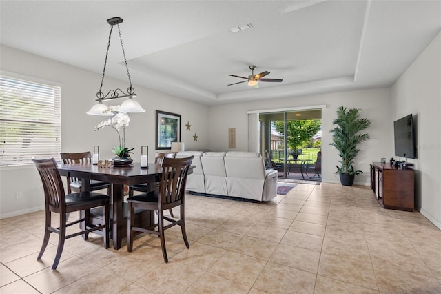 dining room with a raised ceiling, ceiling fan, and light tile patterned floors