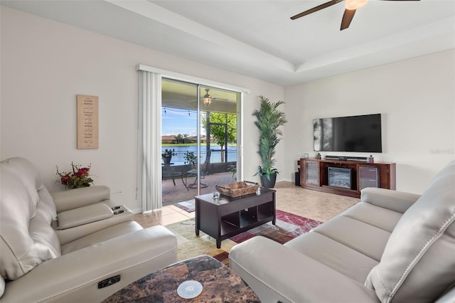 living room with a raised ceiling, ceiling fan, and light tile patterned floors