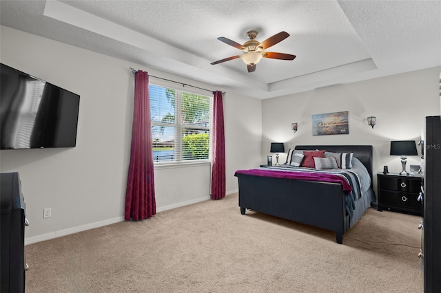 carpeted bedroom featuring ceiling fan, a textured ceiling, and a tray ceiling