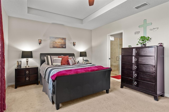 carpeted bedroom featuring connected bathroom, a tray ceiling, and ceiling fan