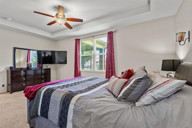 bedroom with a tray ceiling, ceiling fan, and light carpet