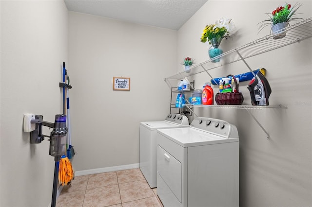 washroom with washer and dryer, light tile patterned floors, and a textured ceiling