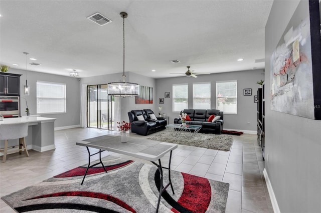 living room featuring light tile patterned flooring and ceiling fan with notable chandelier