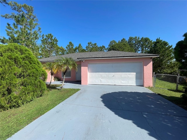 view of front of property with driveway, a garage, stucco siding, fence, and a front yard