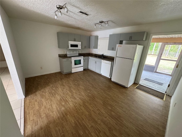 kitchen featuring white appliances, visible vents, dark countertops, dark wood-style flooring, and gray cabinets