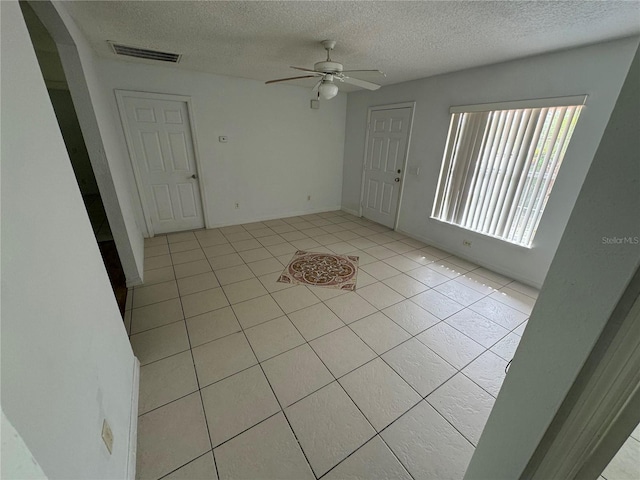 spare room featuring visible vents, ceiling fan, a textured ceiling, and light tile patterned floors