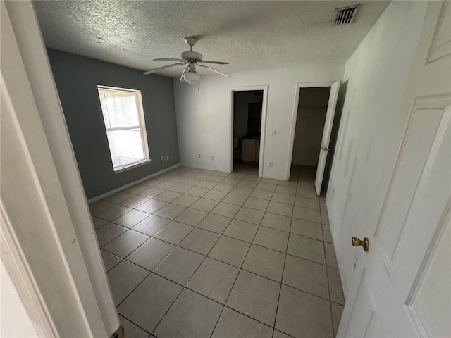 unfurnished bedroom with light tile patterned floors, ceiling fan, visible vents, and baseboards