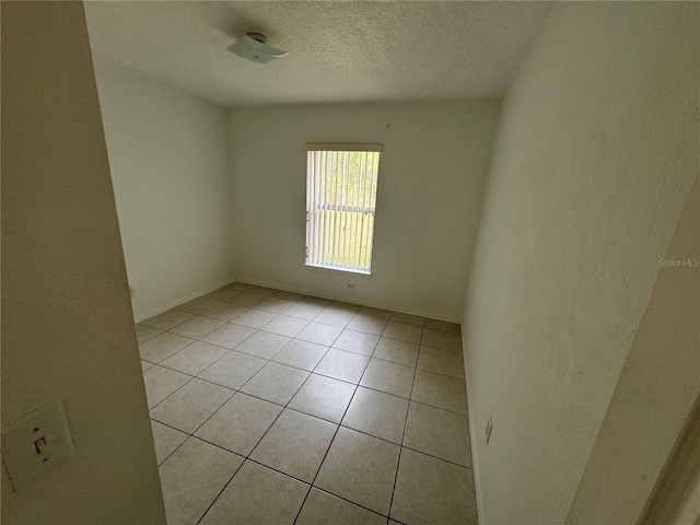 empty room with a textured ceiling and light tile patterned flooring