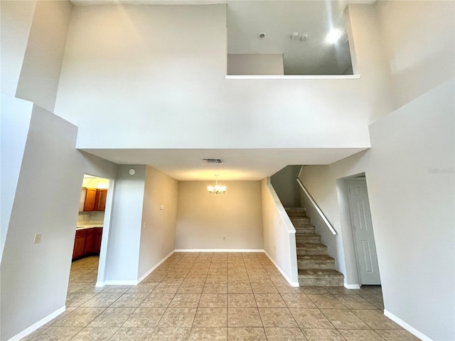 tiled empty room with a high ceiling and a notable chandelier