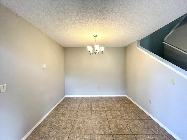 unfurnished dining area with a textured ceiling, a chandelier, and dark tile patterned floors