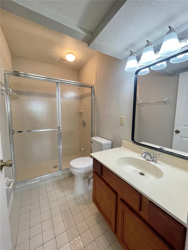 bathroom featuring toilet, vanity, tile patterned flooring, a textured ceiling, and a shower with door