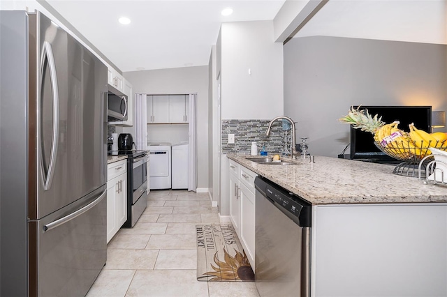 kitchen featuring stainless steel appliances, white cabinets, sink, and light stone countertops