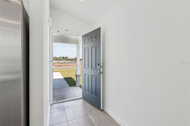 entryway with lofted ceiling, baseboards, and light tile patterned floors