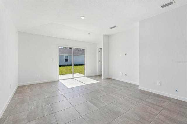 spare room with lofted ceiling, visible vents, and baseboards