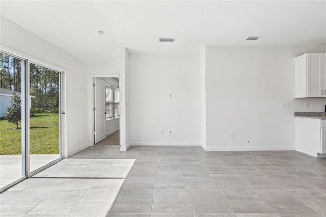 unfurnished living room with light tile patterned floors, baseboards, visible vents, and vaulted ceiling