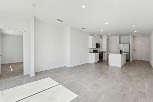 unfurnished living room with recessed lighting, visible vents, vaulted ceiling, and baseboards