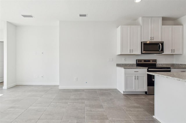 kitchen with visible vents, baseboards, light stone countertops, stainless steel appliances, and white cabinetry