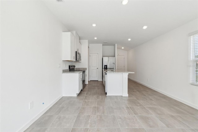 kitchen featuring recessed lighting, appliances with stainless steel finishes, white cabinetry, an island with sink, and baseboards