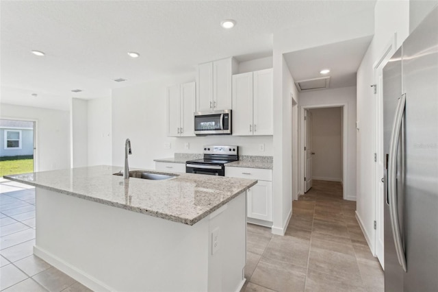 kitchen featuring appliances with stainless steel finishes, a kitchen island with sink, a sink, and white cabinetry