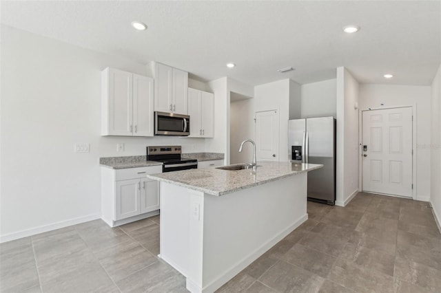 kitchen featuring stainless steel appliances, an island with sink, a sink, and white cabinets