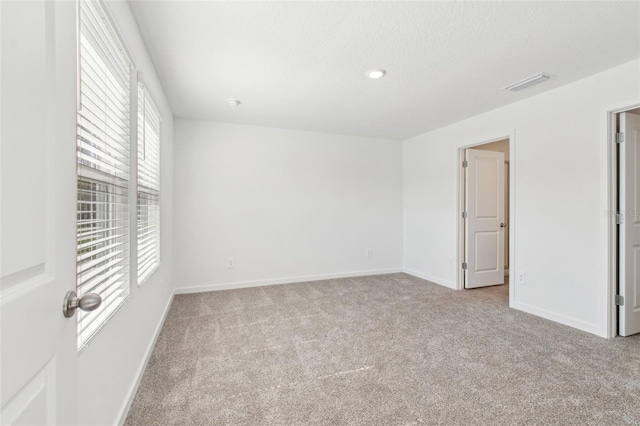 carpeted spare room featuring baseboards and visible vents