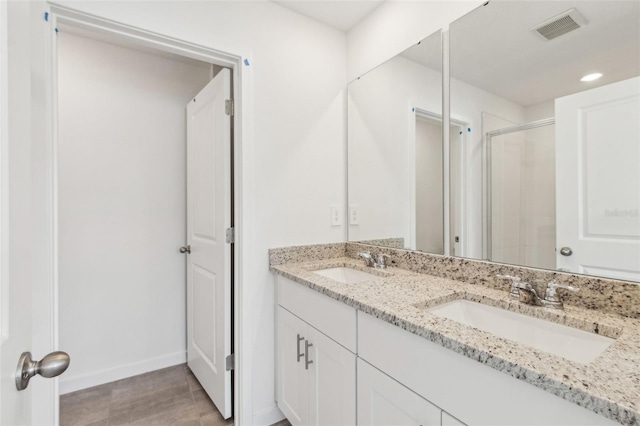 full bath featuring double vanity, a sink, visible vents, and a shower stall