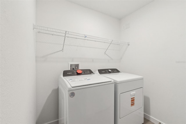 washroom featuring laundry area, baseboards, and separate washer and dryer