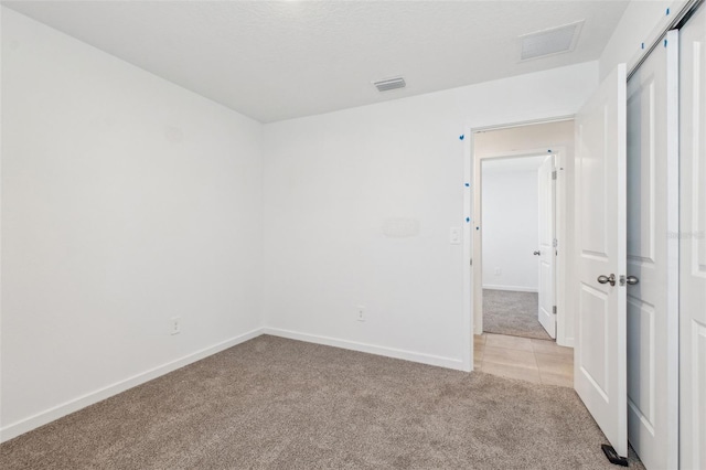 spare room featuring light carpet, baseboards, and visible vents