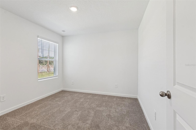 unfurnished room with a textured ceiling, baseboards, and carpet flooring