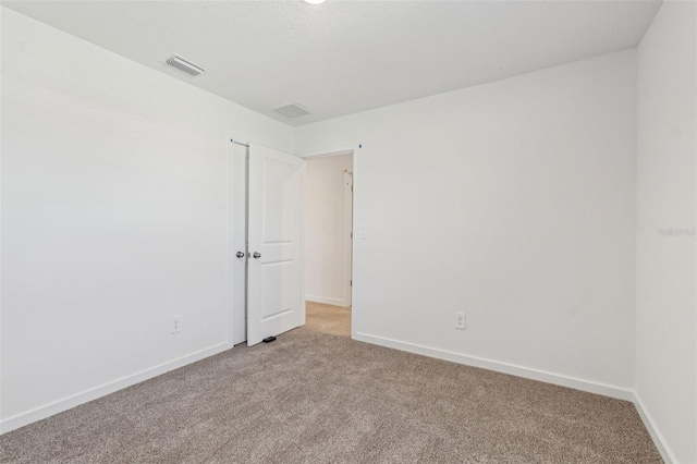 empty room with light colored carpet, visible vents, and baseboards